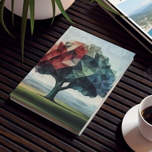 May include: A dark wooden table with a geometric tree art print book, a travel magazine, a white coffee cup, and a potted plant. The tree art print features a colorful, geometric design. The travel magazine has a coastal image on the cover.