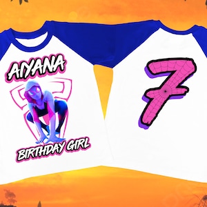 Puede incluir: Una camiseta de b&eacute;isbol blanca y azul con un gr&aacute;fico de mujer ara&ntilde;a rosa y el texto "AYANA BIRTHDAY GIRL" en la parte delantera. La parte posterior de la camiseta tiene un n&uacute;mero 7 rosa con un dise&ntilde;o de telara&ntilde;a.