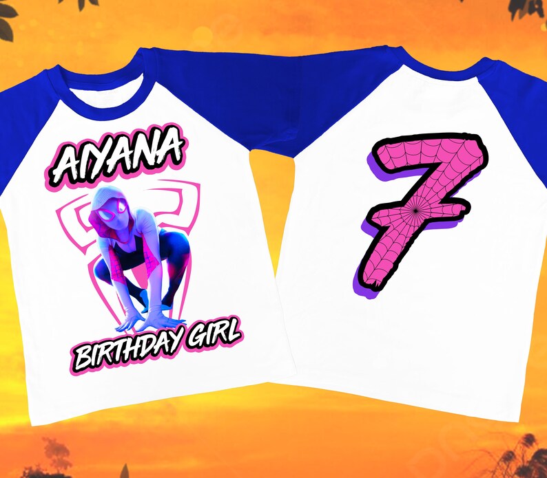 Puede incluir: Una camiseta de b&eacute;isbol blanca y azul con un gr&aacute;fico de mujer ara&ntilde;a rosa y el texto "AYANA BIRTHDAY GIRL" en la parte delantera. La parte posterior de la camiseta tiene un n&uacute;mero 7 rosa con un dise&ntilde;o de telara&ntilde;a.