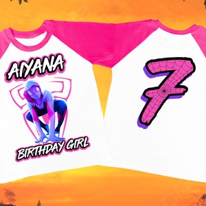 Puede incluir: Una camiseta de b&eacute;isbol blanca y rosa con un gr&aacute;fico de una ara&ntilde;a rosa y blanca en la parte delantera y el nombre "AIYANA BIRTHDAY GIRL" impreso debajo. La parte posterior de la camiseta tiene un n&uacute;mero rosa "7" con un dise&ntilde;o de telara&ntilde;a.