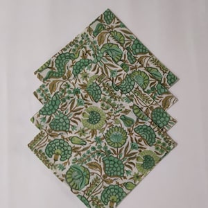 May include: Set of six green and white floral cotton napkins. The napkins are folded in a triangle shape and have a traditional Indian design.
