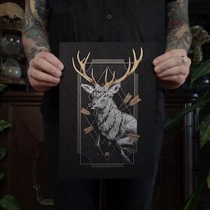 Könnte beinhalten: Ein schwarzer und goldener Druck mit einem stilisierten Hirsch mit Geweih, umgeben von Pfeilen und geometrischen Mustern.