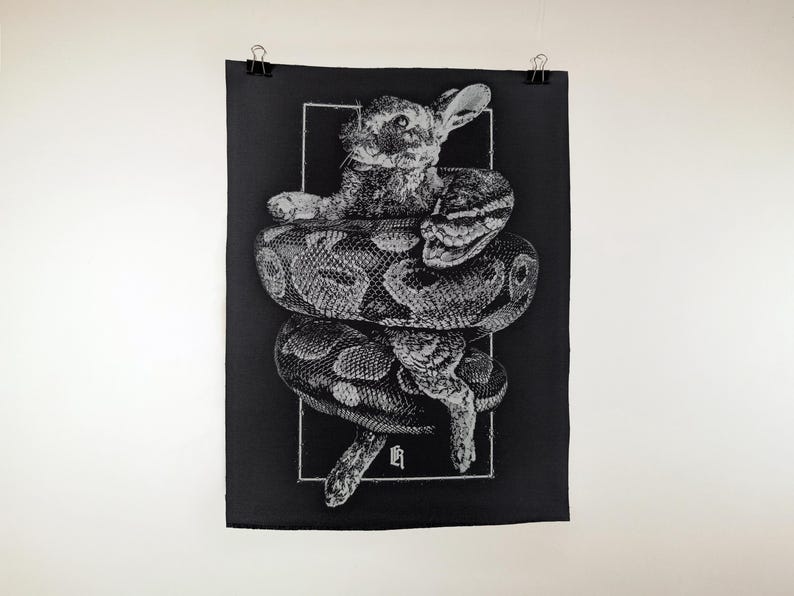 Puede incluir: L&aacute;mina art&iacute;stica en blanco y negro que representa un conejo siendo constre&ntilde;ido por una serpiente. El conejo est&aacute; en el centro, con la serpiente enrollada a su alrededor. La obra est&aacute; sobre un fondo negro.