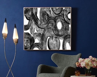May include: Abstract black and white painting with thick brushstrokes in a white frame on a dark blue wall.