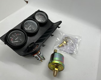 May include: A black dashboard panel with three round gauges labeled VOLT, OIL/KG, and OIL/°C. Also included are a cigarette lighter, a pressure sensor, and a small bag with fittings. Automotive parts.