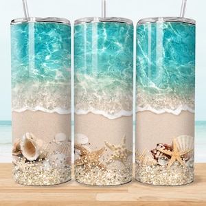 May include: Three stainless steel tumblers with a beach design. The design shows a turquoise ocean, white waves, sandy beach, seashells, and starfish. Each tumbler has a silver lid and a clear straw.