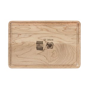 May include: A rectangular wooden chopping board with a light brown finish and a carved border. The board has a graphic of a jar labelled "The Gospel" spreading onto bread, with the words "Go Spread It".