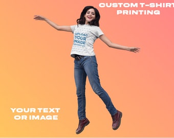 May include: A woman wearing a white t-shirt with the text "UPLOAD YOUR IMAGE 300x300 px" printed on it. She is jumping in the air with her arms outstretched. The background is a gradient of orange and yellow. The text "CUSTOM T-SHIRT PRINTING" is at the top of the image. The text "YOUR TEXT OR IMAGE" is at the bottom of the image.