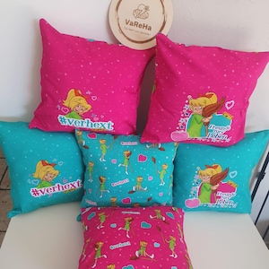 Könnte beinhalten: Sechs rosa und türkisfarbene Kissen mit einer Zeichentrickfigur eines Mädchens und dem Text "#verhext" und "Freunde fürs Leben".