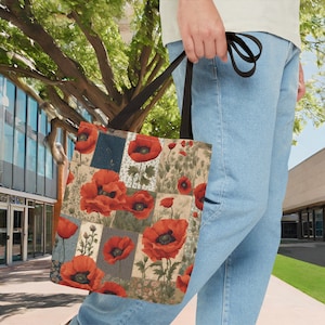 May include: A black tote bag with a patchwork design featuring red poppies on a cream background. The bag has a long black strap.