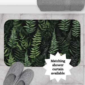 May include: A black bath mat with a green fern pattern. The text "Matching shower curtain available" is in a white starburst shape.
