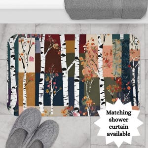 May include: A colorful bath mat with a patchwork design featuring white birch trees and autumnal foliage. The mat has a non-slip backing and is machine washable. Matching shower curtain available.