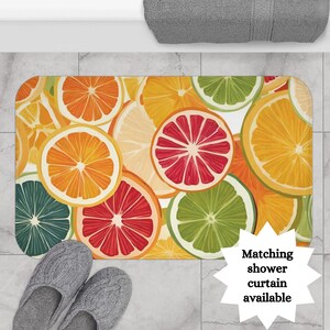 May include: A colorful bath mat with a citrus fruit design. The mat features slices of oranges, lemons, limes, and grapefruits in a white background.  Matching shower curtain available.
