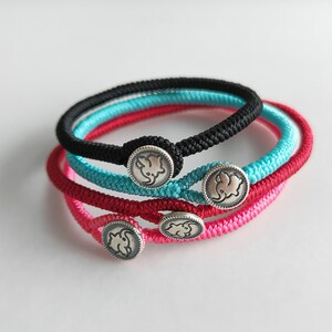 May include: Four colorful braided bracelets with silver elephant charms. The bracelets are black, red, turquoise, and pink.