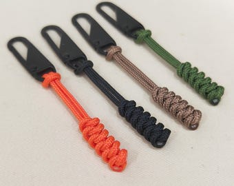 Puede incluir: Cuatro llaveros con clips metálicos negros y cordones trenzados de colores. Los cordones son naranja, negro, marrón y verde.