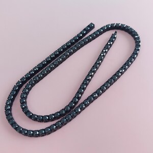 May include: A black tennis chain necklace with a row of black cubic zirconia stones.