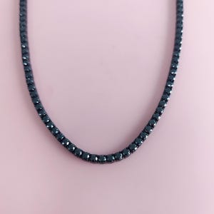 May include: A black tennis chain necklace with a row of small black diamonds.