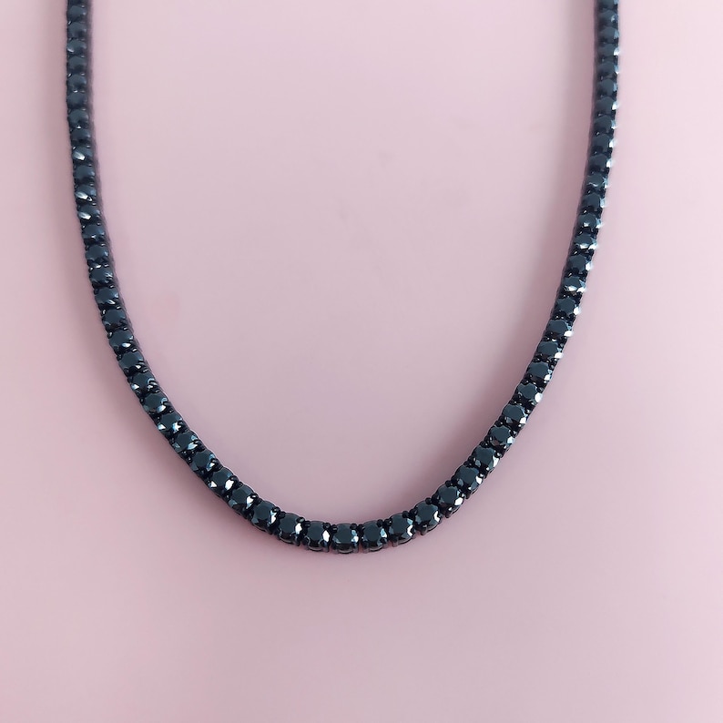 May include: A black tennis chain necklace with a row of small black diamonds.