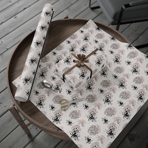 May include: A roll of white wrapping paper with a repeating pattern of black and brown octopus illustrations. A brown ribbon is tied around a gift box wrapped in the paper.