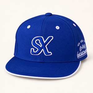 May include: A royal blue baseball cap featuring a white embroidered SX logo on the front panel. The cap has a flat brim with a white edge, white eyelets on the crown, and a white graphic design embroidered on the side panel of the hat.