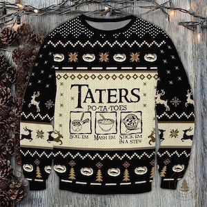 May include: Black knitted jumper with a cream-coloured central panel displaying the text "TATERS PO-TA-TOES" and cooking instructions. The jumper has a repeating pattern of snowflakes, reindeer, and trees. The sleeves and upper portion are black.