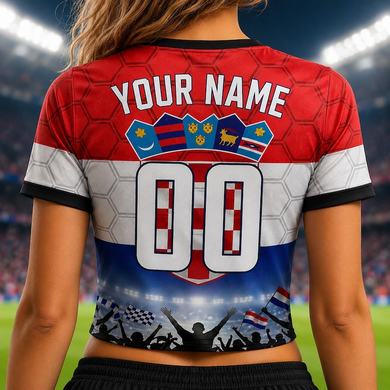 May include: A short-sleeved jersey featuring a red, white, and blue color scheme with a honeycomb pattern. The back displays the text YOUR NAME above a crest with five shields and the large white number 00. The bottom shows a stadium crowd graphic.