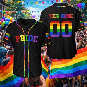 May include: Black baseball jersey with rainbow accents and the word "PRIDE" in rainbow colors across the chest. The back of the jersey has the text "YOUR NAME" above the number "00" in rainbow colors. The sleeves have a rainbow fist graphic.