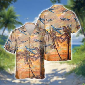 May include: A short-sleeved button-down shirt featuring a tropical sunset scene with palm trees and small airplanes. The shirt's design includes a warm color palette of orange, yellow, and brown, with blue and white airplanes scattered across the fabric.