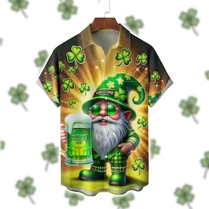 May include: Short-sleeved button-up shirt featuring a St. Patrick's Day gnome holding a green beer. The shirt has a green and gold background with shamrocks. The gnome wears a green hat with the word "WELCOME" and green sunglasses. The beer mug reads "HAPPY ST. PATRICK'S DAY".
