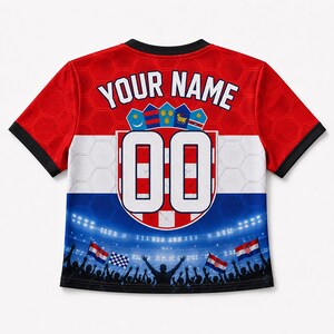 May include: A short-sleeve jersey featuring a red, white, and blue color scheme with a honeycomb pattern. The back displays the text YOUR NAME above a shield with the number 00, and a graphic of a stadium crowd with flags at the bottom hem.