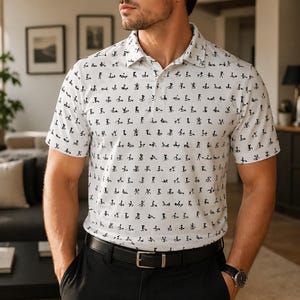 May include: White polo shirt with a black pattern of small figures. The shirt has short sleeves and a collared neckline. The person is wearing a black belt and black pants.