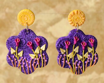 Op de afbeelding: Paarse bloemoorbellen met gele accenten. De oorbellen hebben een bloemmotief met roze bloemen en gele bladeren. De oorbellen zijn bevestigd aan een gele schijf.