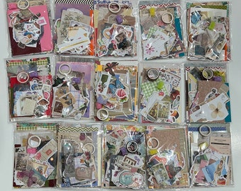 May include: A collection of 10 clear plastic bags filled with various colorful paper ephemera, including stickers, washi tape, and patterned paper. The bags are arranged in three rows of three, with one bag at the bottom center.