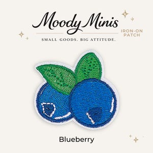 May include: An embroidered iron-on patch featuring two blue blueberries with green leaves. The text Moody Minis, IRON-ON PATCH, SMALL GOODS. BIG ATTITUDE., and Blueberry is printed around the patch. The design uses blue, green, and white thread.