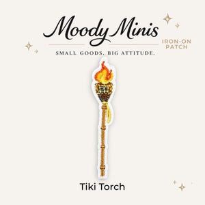 May include: An embroidered iron-on patch featuring a tiki torch with a golden brown bamboo-style pole, a dark brown woven head, and a bright orange and yellow flame. The text Moody Minis, Iron-On Patch, Small Goods. Big Attitude., and Tiki Torch is visible.
