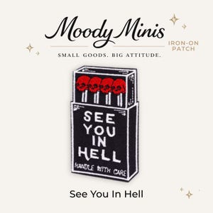 May include: An iron-on patch shaped like a matchbox with a black background and white border. The design features four red skull-topped matches and the white text "SEE YOU IN HELL" followed by "HANDLE WITH CARE" printed on the front of the box.
