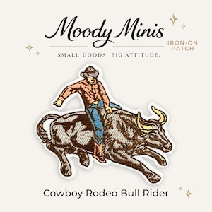 May include: An embroidered iron-on patch featuring a cowboy riding a bucking bull. The rider wears a brown hat, peach shirt, blue jeans, and brown boots. The bull is dark brown with yellow horns. Text reads Moody Minis, IRON-ON PATCH, SMALL GOODS. BIG ATTITUDE. Cowboy Rodeo Bull Rider.