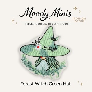 May include: An embroidered iron-on patch featuring a light green pointed hat with a small white flower and dark green foliage accents. The text Moody Minis, Iron-On Patch, Small Goods. Big Attitude., and Forest Witch Green Hat are visible.