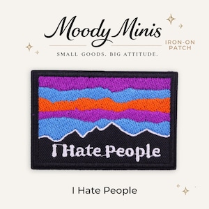 May include: A rectangular iron-on patch featuring an embroidered mountain landscape design with horizontal bands of purple, light blue, and orange thread above a black base. The white text "I Hate People" is stitched across the black section.