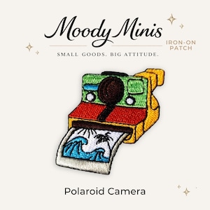 May include: An embroidered iron-on patch shaped like a vintage instant camera. The camera is green, red, and yellow, with a white photo ejecting from the front featuring a blue ocean wave and a black palm tree. Text reads Moody Minis and Polaroid Camera.