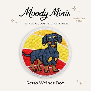 May include: A circular iron-on patch featuring a black and tan dachshund dog standing against a background of horizontal yellow and red stripes. The text Moody Minis, IRON-ON PATCH, SMALL GOODS. BIG ATTITUDE., and Retro Weiner Dog are visible.