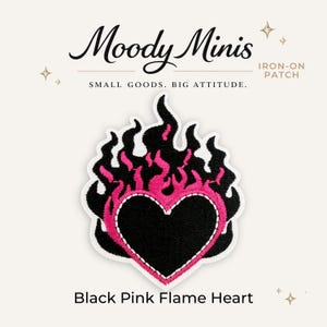 May include: An embroidered iron-on patch featuring a black heart surrounded by vibrant pink and black flames. The text Moody Minis, Small Goods. Big Attitude. Iron-On Patch, and Black Pink Flame Heart are printed around the central heart design.