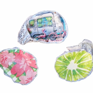 May include: Three oyster shells with painted designs. One shell features a pink flamingo and a vintage camper with a bicycle. Another shell has a green and white lime design. The third shell has a pink floral design on a green and white checkered background.