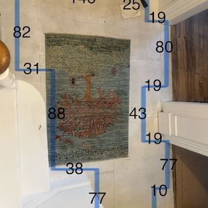 Pode incluir: Um tapete azul e bege com um desenho de &aacute;rvore em laranja e vermelho. O tapete tem 88 polegadas de comprimento e 43 polegadas de largura. O tapete est&aacute; sobre um piso branco com fita azul que delimita as dimens&otilde;es do tapete.