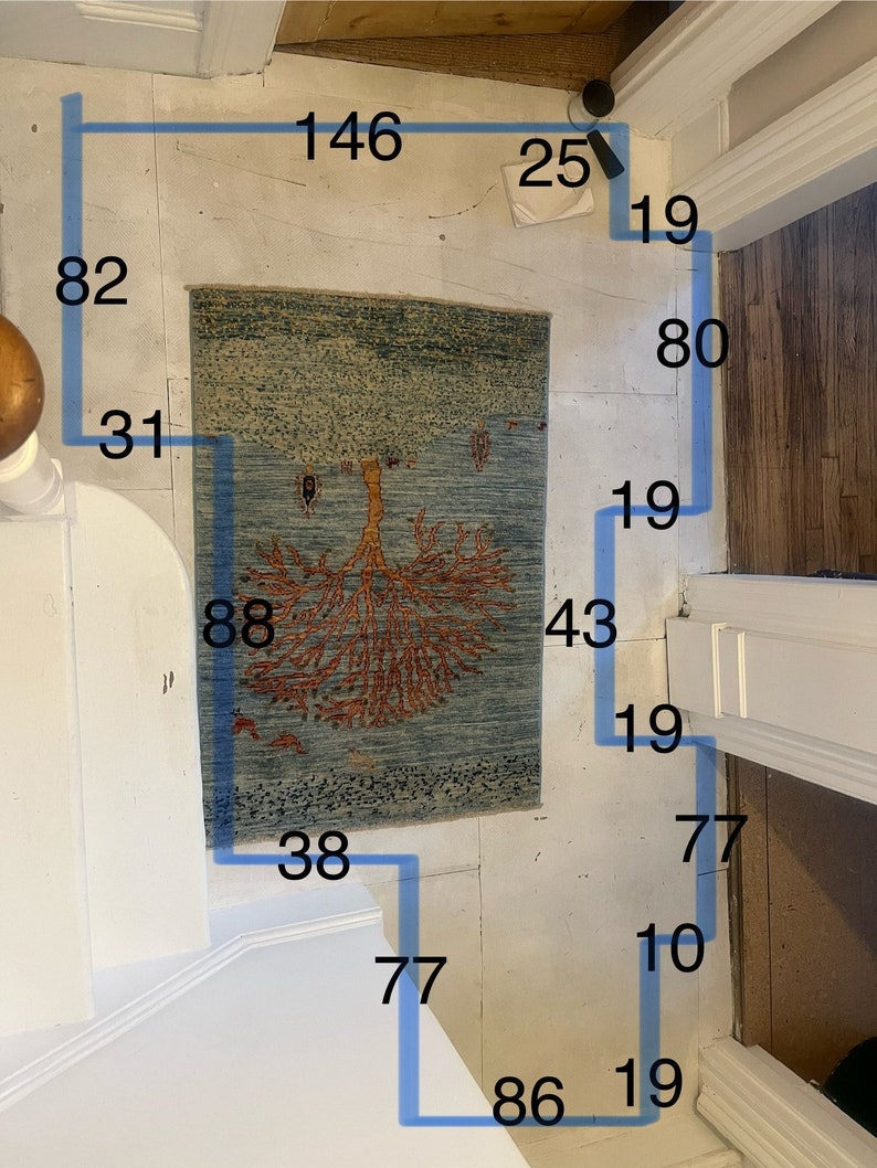 Pode incluir: Um tapete azul e bege com um desenho de &aacute;rvore em laranja e vermelho. O tapete tem 88 polegadas de comprimento e 43 polegadas de largura. O tapete est&aacute; sobre um piso branco com fita azul que delimita as dimens&otilde;es do tapete.