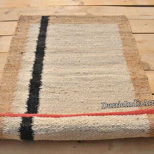 May include: A rolled up jute rug with a black stripe and a red border. The rug is made of natural fibers and has a rustic look.