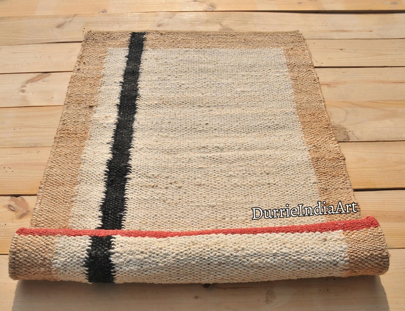 May include: A rolled up jute rug with a black stripe and a red border. The rug is made of natural fibers and has a rustic look.