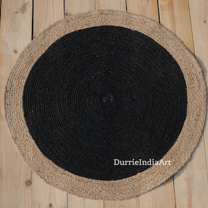 May include: Round jute rug with a black center and a natural jute border. The rug has a woven texture and is approximately 30 inches in diameter.
