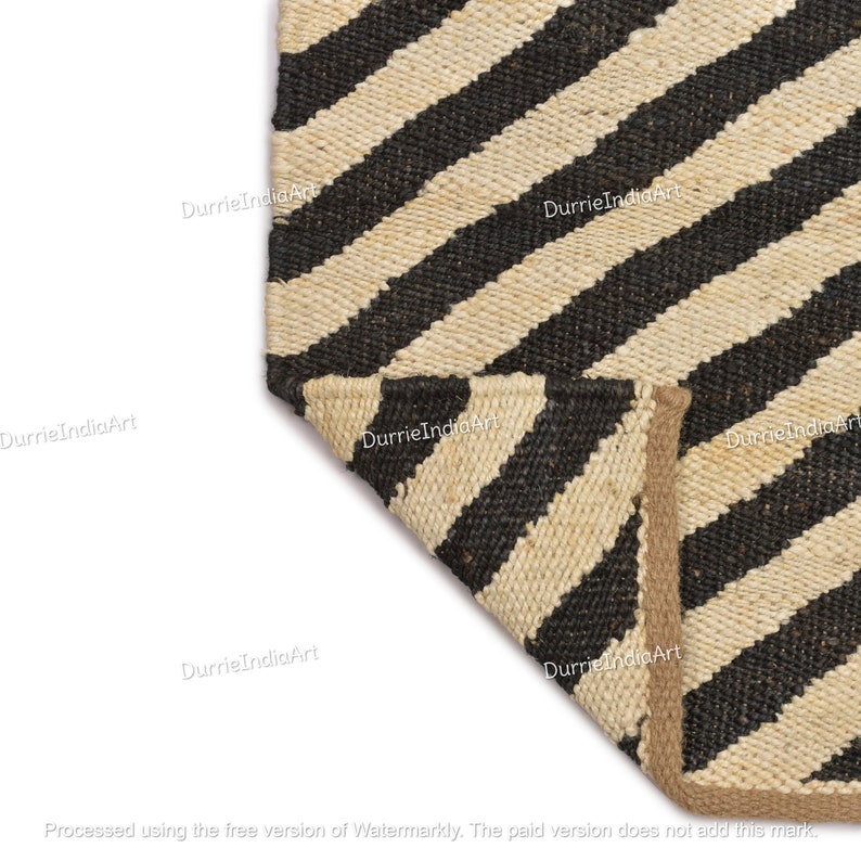 May include: Close-up of a black and natural jute rug with diagonal stripes. The rug has a natural jute border.