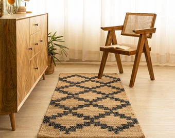 May include: A black and natural jute rug with a geometric pattern. The rug is placed in front of a wooden dresser and a wooden chair with a cane seat.